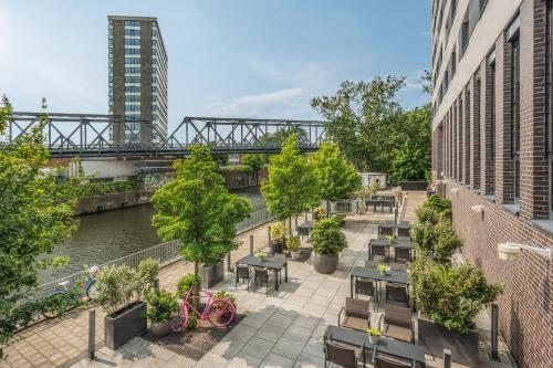a patio with tables and chairs next to a river at INNSiDE by Meliá Hamburg Hafen in Hamburg