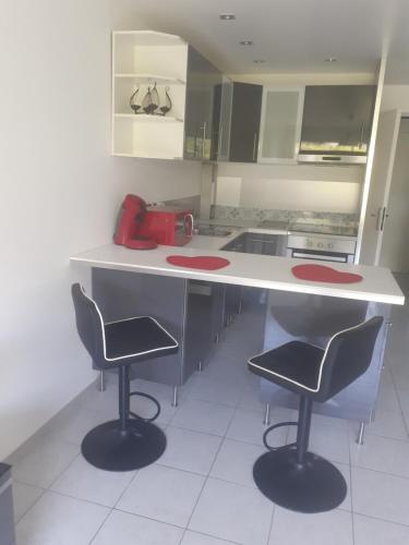 une cuisine avec deux chaises et un comptoir avec un appareil dans l'établissement Charmant studio au Ponant, à La Grande Motte