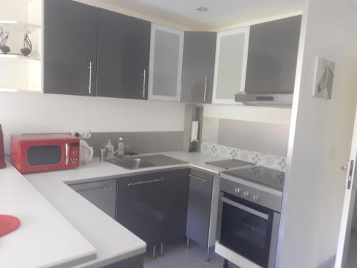 - une cuisine avec des placards noirs et blancs et un four micro-ondes dans l'établissement Charmant studio au Ponant, à La Grande Motte