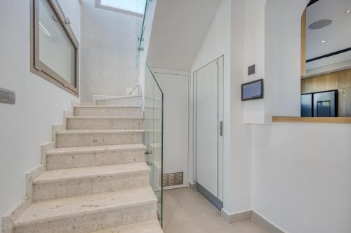 a staircase in a house with white walls and a glass door at Villa Stafida Kassiopi in Kassiopi