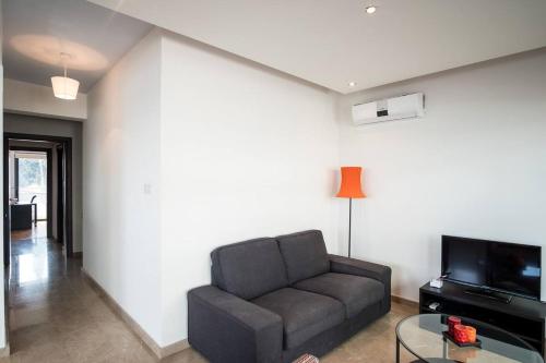 a living room with a couch and a tv at Dios Ponte Finikoudes Beachfront in Larnaka