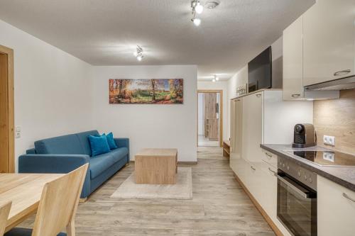 a living room with a blue couch and a kitchen at Haus Peter Falch in Pettneu am Arlberg