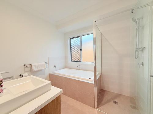 un bagno bianco con vasca e lavandino di Park Ridge Retreat 4BR 2Bath with Outdoor a Park Ridge