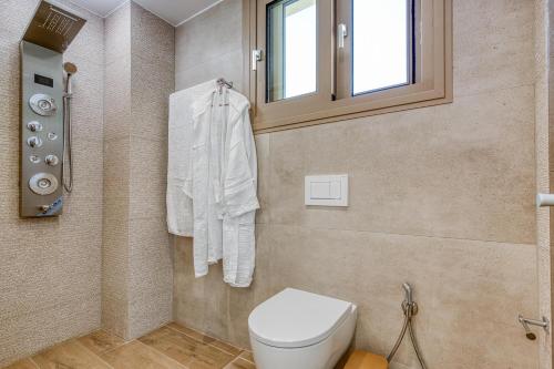 a bathroom with a toilet and a window at Villa Stafida Kassiopi in Kassiopi