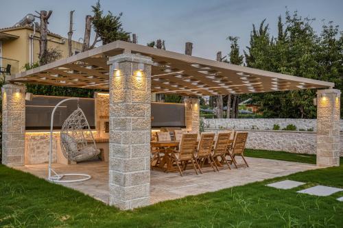 a pergola with a table and chairs under it at Villa Stafida Kassiopi in Kassiopi
