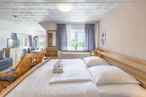 Un dormitorio con una cama grande con sábanas blancas. en Haus Seeblick _ Wohnung 2, en Dagebüll