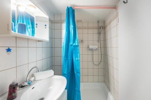 baño con cortina de ducha azul y lavamanos en Haus Seeblick _ Wohnung 2, en Dagebüll