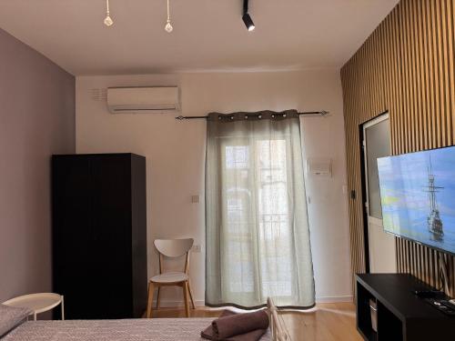 a bedroom with a large window and a television at Bentley Floriana Suites in Il-Furjana