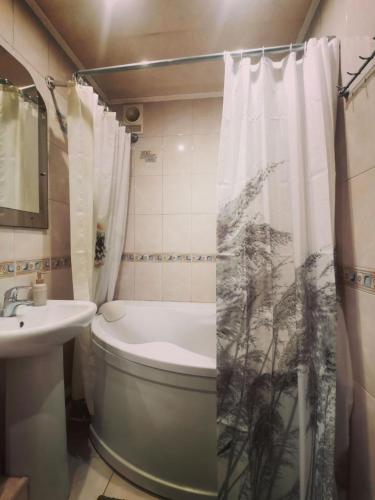 a bathroom with a toilet and a sink and a shower curtain at Міні готель Еней in Kyiv