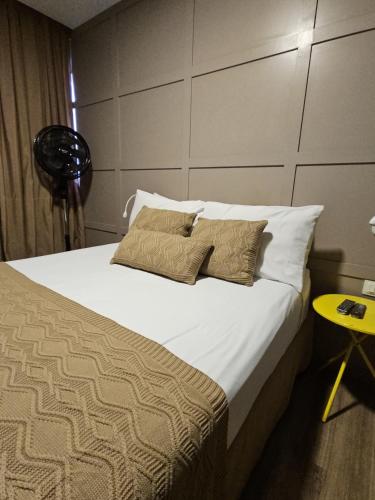 a bedroom with a bed with two pillows and a table at Hospedaria Santiago in Teresópolis