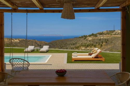 a patio with a table and chairs and a pool at Oliva Emerald Eco - Secluded Off-Grid Vineyard Villa in Káto Váthia