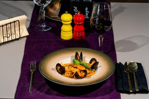 a bowl of pasta on a table with a glass of wine at Sierra in Piteşti