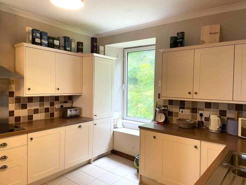 Una cocina con gabinetes blancos y una ventana. en McCaig's Tower Apartment, en Oban