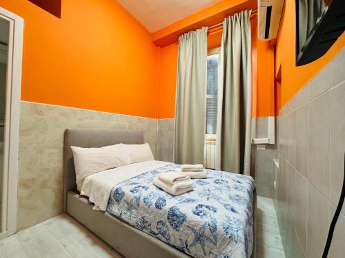 a bedroom with orange walls and a bed with towels on it at Oscar Rooms in Rome