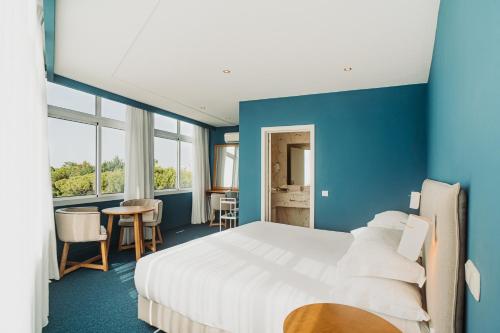 a hotel room with a large bed and blue walls at Velamar Boutique Hotel - Adults Friendly in Albufeira