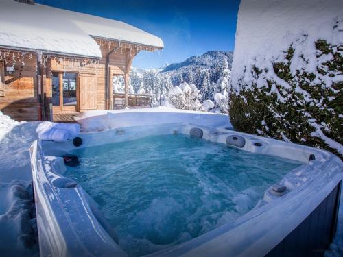 un bain à remous dans la neige à côté d'un bâtiment dans l'établissement Chalet Alex - OVO Network, à Saint-Jean-de-Sixt