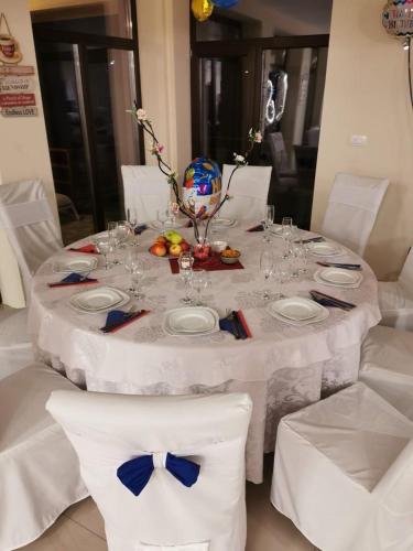 a white table with white chairs and a table with plates and glasses at Eden Villa in Ocina de Jos