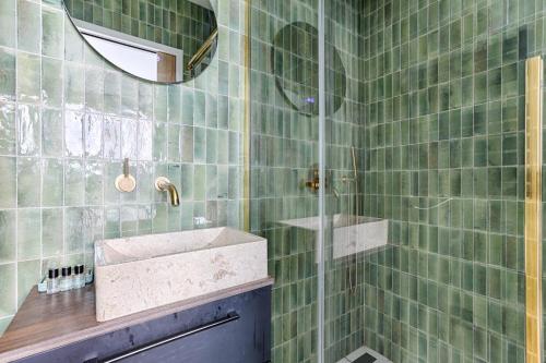 une salle de bain carrelée verte avec un lavabo et un miroir dans l'établissement Maison de charme au coeur de Batignolles, à Paris