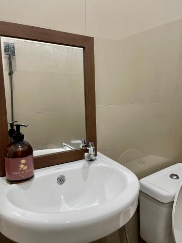 a bathroom with a sink and a mirror and a toilet at Iwa Hotel in Tagbilaran City