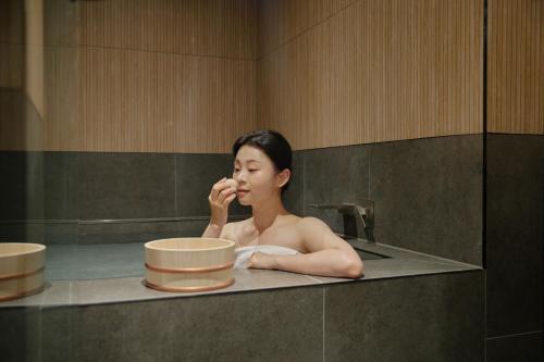 a woman sitting in a bath tub brushing her teeth at Yuhyu Ryokan Hotel in Seoul
