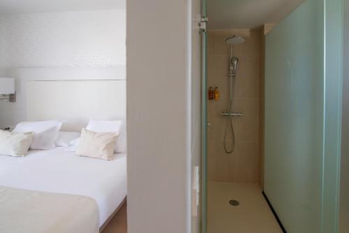 a bedroom with a shower and a white bed at Aequora Lanzarote Suites in Puerto del Carmen