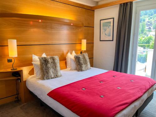 a bedroom with a large bed with a red blanket at Hotel Les Vallées Labellemontagne in La Bresse
