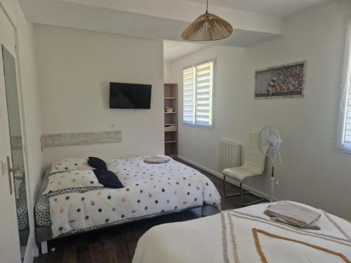 a white bedroom with two beds and a chair at Le Nid Cabailla in Coimères