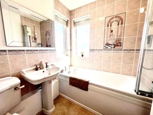 ミルトン・キーンズにあるModern 5 Bedroom House with Parking in Central Milton Keynesの洗面台、浴槽、トイレを備えたバスルーム