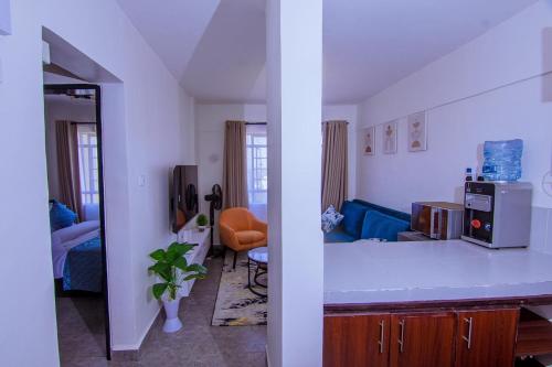 a kitchen with a counter and a living room at Saki Nest Homes in Kisumu