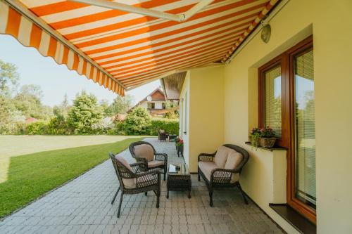 a patio with chairs and awning on a house at Penzion Drak in Liptovský Mikuláš