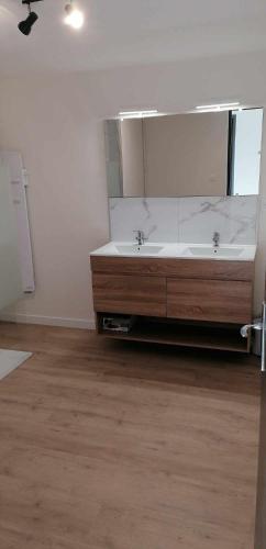 La salle de bains est pourvue d'un grand miroir et d'un lavabo. dans l'établissement Maison au cœur du Sancy, à Férérolles