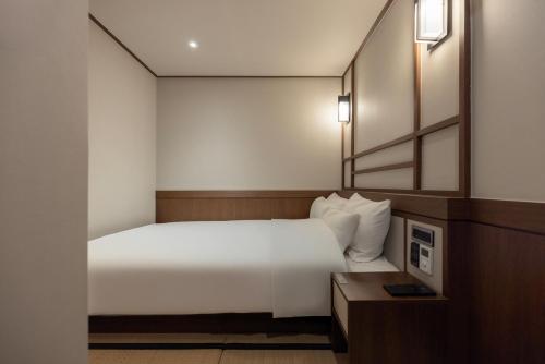 a hotel room with a white bed and a mirror at Yuhyu Ryokan Hotel in Seoul