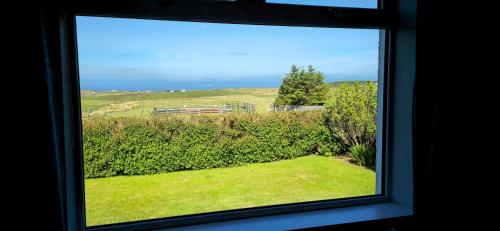 a window with a view of a field of grass at Fladda Chuain Holiday Home in Kilmuir