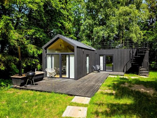a small house with a deck in a yard at W Ogrodzie Dla Gości in Sasino