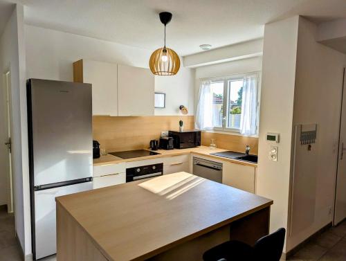 a kitchen with a refrigerator and a table in it at Maison T4 jardin, garage, terrasse, bureau in Dax