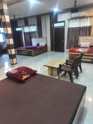 a room with two beds and a table and chairs at Shree Ram Saroj - Aksh Dham in Vrindāvan