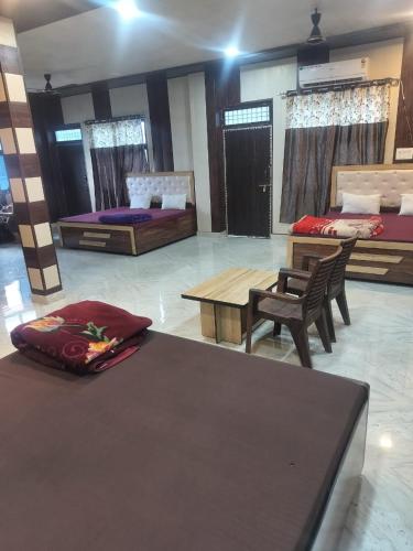 a room with two beds and a table and chairs at Shree Ram Saroj - Aksh Dham in Vrindāvan