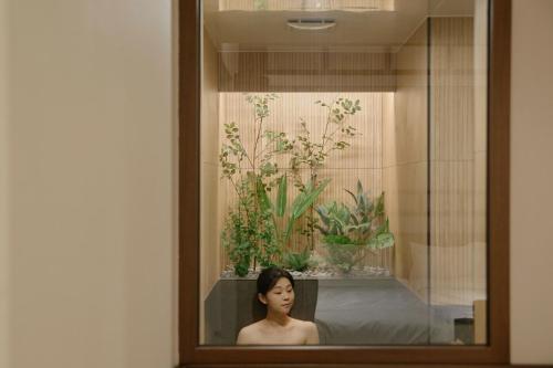 a woman is in a bath tub with plants at Yuhyu Ryokan Hotel in Seoul