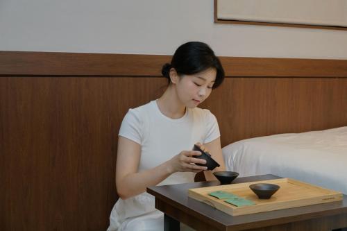 a woman sitting at a table looking at her cell phone at Yuhyu Ryokan Hotel in Seoul