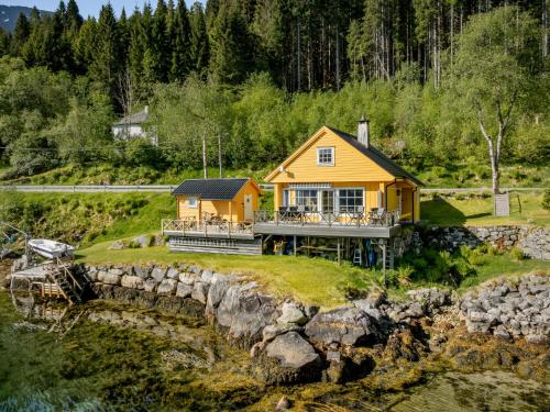 a yellow house on a hill next to a river at Holiday Home Eseviki by Interhome in Balestrand