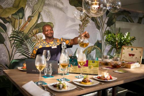 a man pouring a glass of wine at a table at The Cape Milner in Cape Town