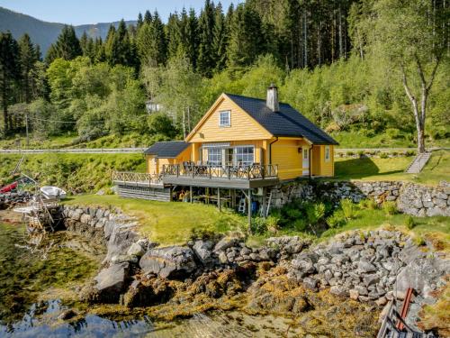 a yellow house on a hill next to a river at Holiday Home Eseviki by Interhome in Balestrand