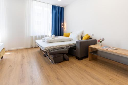 a bedroom with a bed and a couch and a table at Chérisy Hotel Konstanz - Self Check-in Only in Konstanz