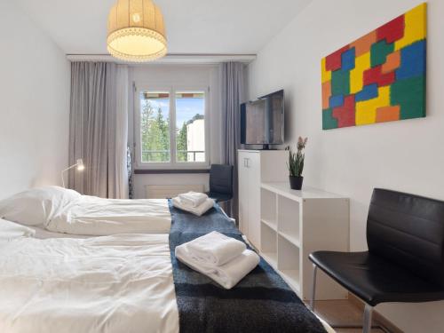 a bedroom with a bed and a chair and a television at Apartment Allod Park Haus B 202 by Interhome in Davos
