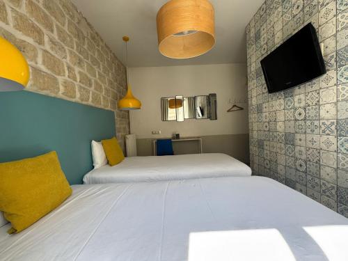 a bedroom with two beds and a tv on the wall at Le Regent Montmartre by Hiphophostels in Paris