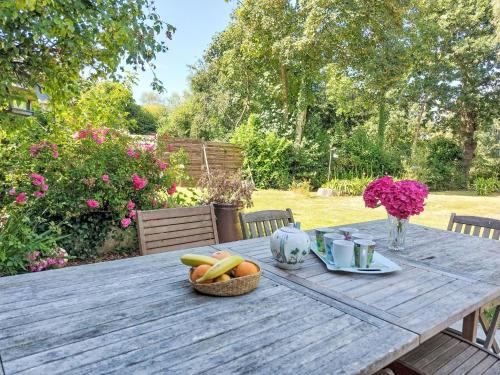 a wooden table with a basket of fruit on it at Holiday Home Les Agapanthes by Interhome in Languenan