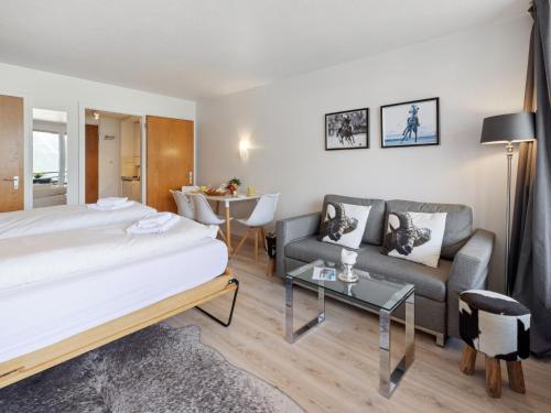 Un dormitorio con una cama, un sofá y una mesa. en Apartment Promenade - Utoring-60 by Interhome, en Arosa