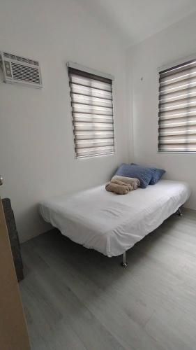 a bed in a white room with two windows at 3-Bedroom House in NorthPoint in Talisay