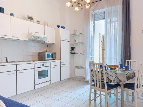 une cuisine avec des placards blancs et une table avec une salle à manger dans l'établissement Apartment de la Plage et d'Angleterre by Interhome, à Royan