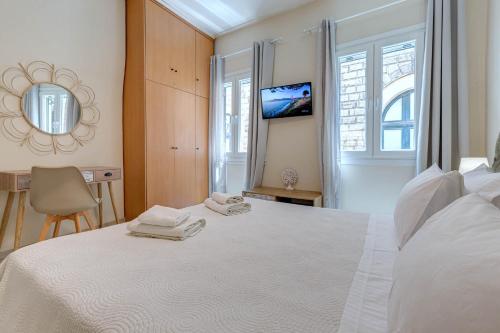 - une chambre blanche avec un lit blanc et un miroir dans l'établissement Gabriel's cozy central house in Corfu town, à Corfu